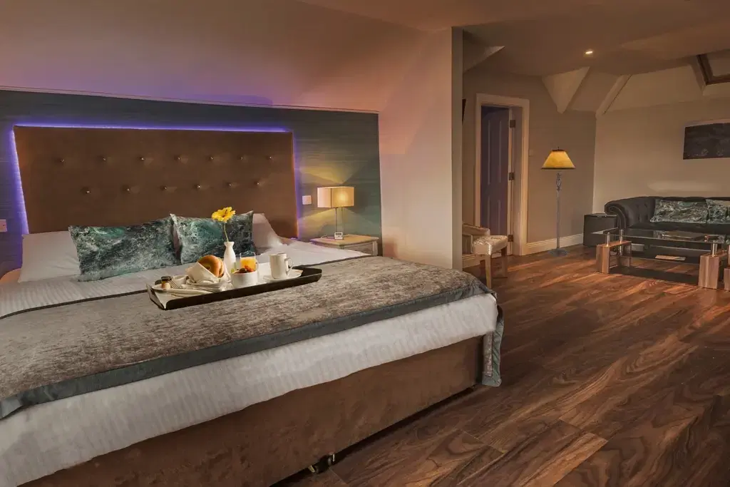 Hotel room with a double bed, breakfast tray, sofa and warm lighting