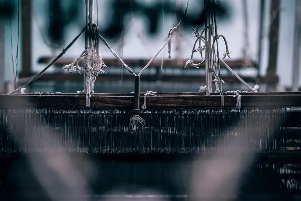 Warp threads on a power loom inside a textile factory in India