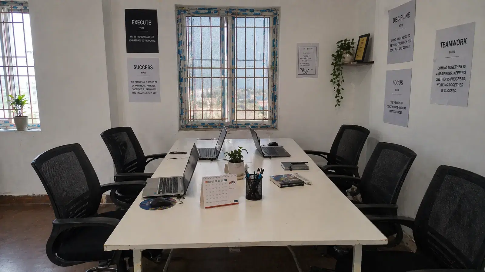 RED SAG workspace in Tiruppur: a shared white desk with laptops, black office chairs and motivational posters on the walls