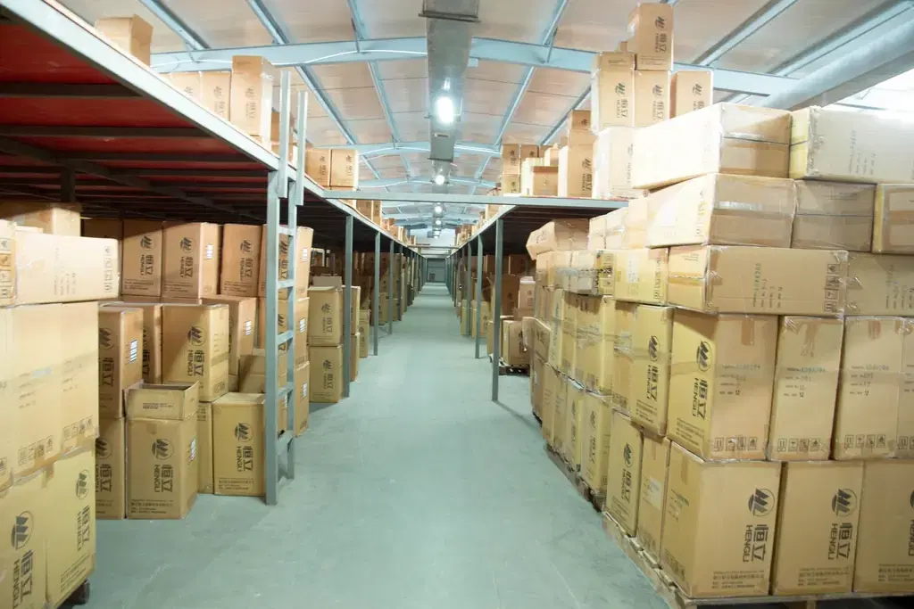Stockroom aisle lined with stacked cardboard cartons, showing small business inventory management