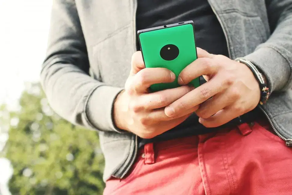 Man typing a message on a green smartphone, representing WhatsApp Business automation