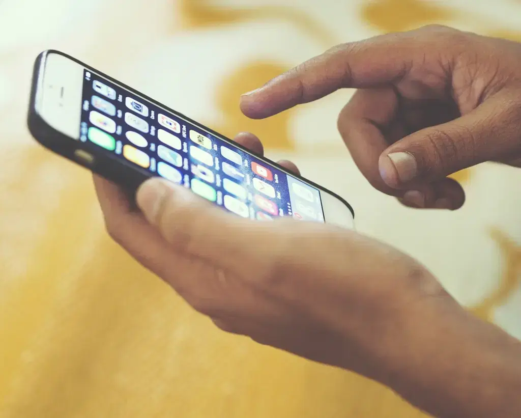 Hand tapping a mobile app on a smartphone screen, the kind of app Flutter developers build
