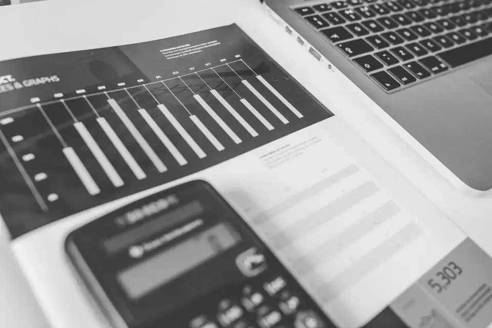 Printed financial statement with a bar chart and calculator beside a laptop, for account aggregator analysis