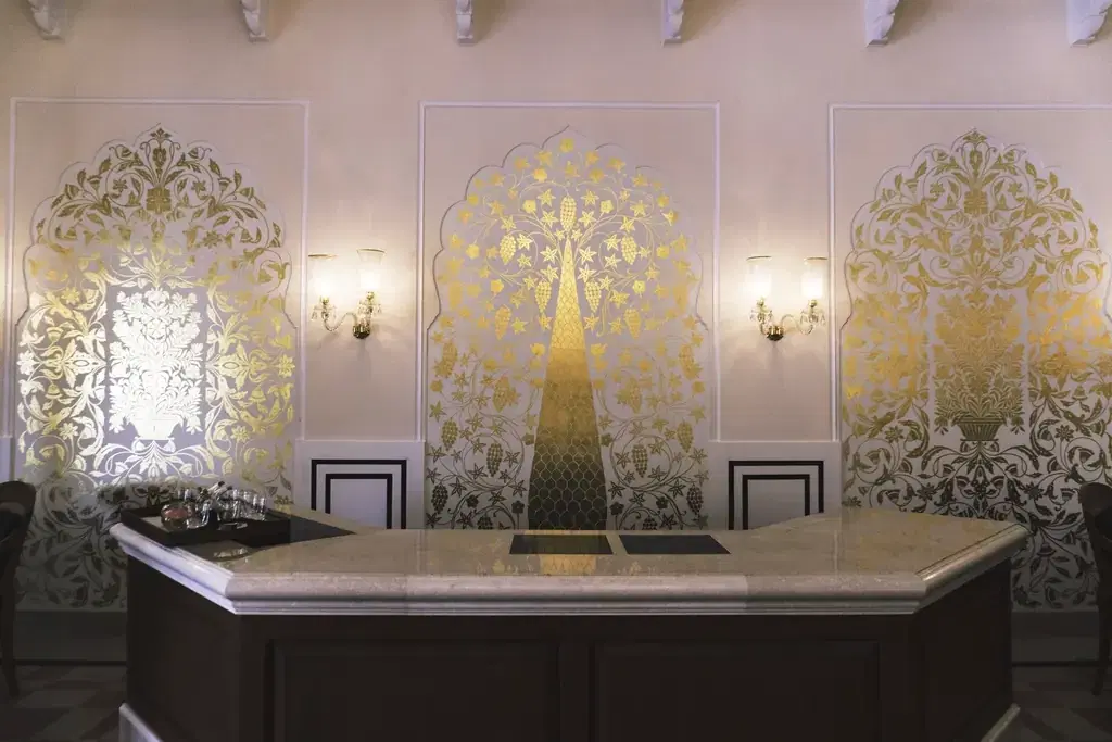 Hotel reception desk with an ornate gold wall, where a booking system manages check-ins