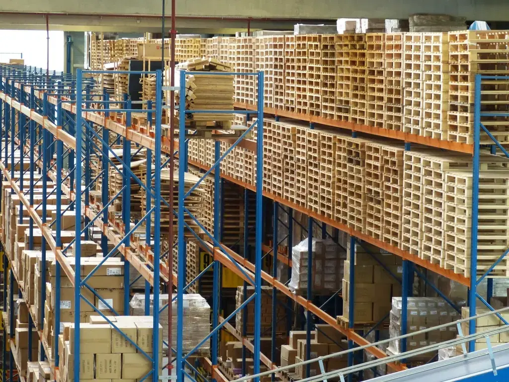 Tall warehouse racks stacked with cartons and pallets, tracked by inventory management software