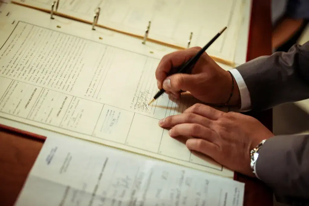 Borrower signing a loan agreement in a bound ledger with a pen