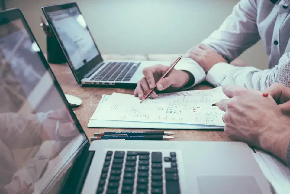 Agency and developer reviewing white label project notes beside two open laptops